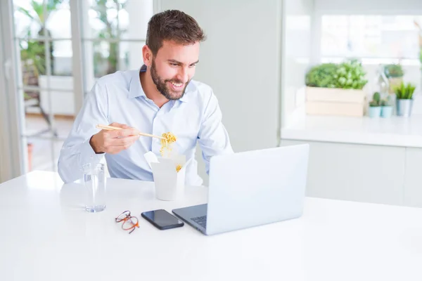 Uomo d'affari mangiare take away asiatico tagliatelle cibo mentre lavoro u — Foto Stock