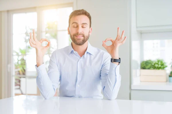 Handsome business man relax and smiling with eyes closed doing meditation gesture with fingers. Yoga concept.