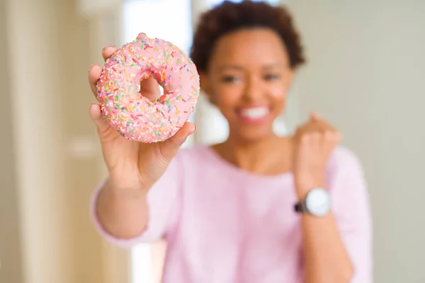 感情を応援して誇りに思って叫んでと勝利と非常に興奮して 成功を祝ってのピンク シュガー ドーナツを食べる若いアフリカ系アメリカ人女性 — ストック写真