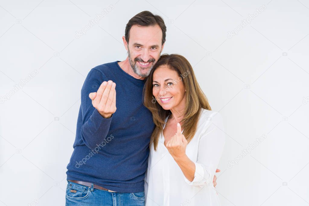 Beautiful middle age couple in love over isolated background Beckoning come here gesture with hand inviting happy and smiling