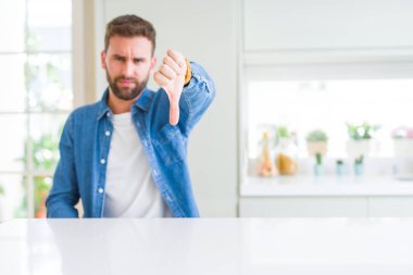 Yakışıklı adam evde mutsuz ve kızgın ret gösterilen ve başparmak aşağı hareketi ile negatif arıyorum. Kötü ifade.