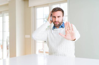 Kulaklık takmış ve açık eliyle dur işareti ile ciddi ve kendine güvenen ifade, savunma hareketi yaparken müzik yakışıklı adam