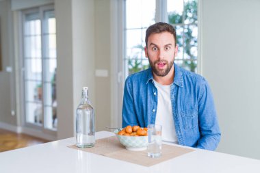 Yakışıklı adam yeme makarna köfte ve domates sosu evde korkuyor ve sürpriz ifade ile şok ile korku ve yüz heyecanlı.