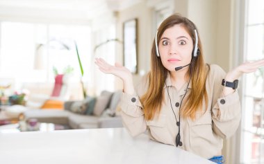 Yeniden office clueless ve şaşkın bir ifadeyle kollar ve eller kaldırdı, kulaklık giyen güzel genç operatör kadın. Şüphe kavramı.