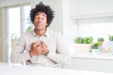 Afrika kökenli Amerikalı adam evde kapalı gözler ile göğüs ellerinde ve yüzünde minnettar jest ile gülümseyen. Sağlık kavramı.