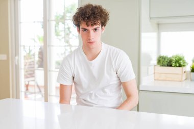 Sorunu nedeniyle ev şüpheci ve sinir, papatyanın üzgün beyaz t-shirt giyen genç yakışıklı adam. Negatif kişi.
