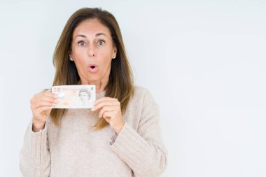 10 pound banknot izole arka plan üzerinde bir sürpriz yüz, korkuyor ve heyecanlı korku ifadesi ile şok korkmuş tutan orta yaş kadın