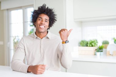 Afrika kökenli Amerikalı adam evde seyir ve başparmak yanında yukarıyı mutlu yüz ile gülümseyen.