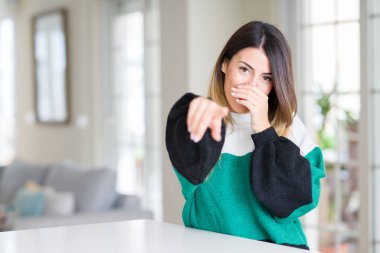 Sizin parmak el kamerasıyla ağzına, utanç ifadesi işaret eden ev gülme, kış kazak giyen genç güzel kadın
