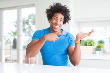 Afrikalı-Amerikalı adam evde hayret ve gülümseyerek kameraya el ile sunulması ve parmak ile işaret ederken.