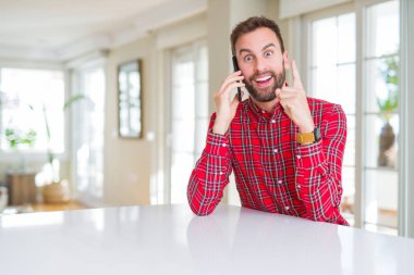 Smartphone üzerinde bir fikir ya da soru işaret parmağı gülen yüz, bir numara ile sürpriz konuşan yakışıklı adam