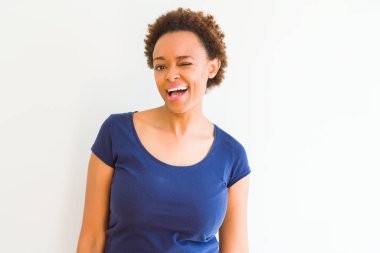 Seksi bir ifadeyle, neşeli ve mutlu yüzünü kameraya bakarak göz kırpıyor beyaz arka plan üzerinde genç güzel bir Afrikalı-Amerikalı kadın.