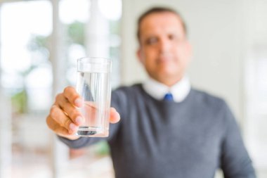 Orta yaş erkek ciddi düşünme akıllı yüzünde kendinden emin bir ifade ile evde su içme