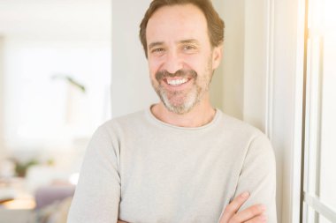 Evde kameraya bakarak gülümseyen yakışıklı orta yaş erkek