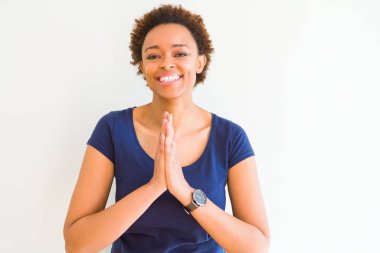 Young beautiful african american woman over white background praying with hands together asking for forgiveness smiling confident. clipart