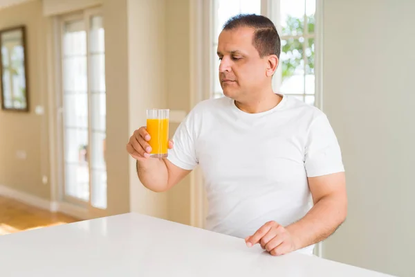 中年男子在家喝了一杯橙汁 聪明的脸上自信的表情思考着严肃 — 图库照片