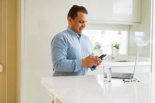 Uomo di mezza età che lavora con il computer portatile e utilizzando smartphone — Foto Stock