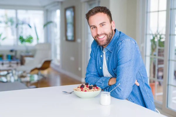 Hombre guapo desayunando comiendo cereales en casa y sonriendo — Foto de Stock