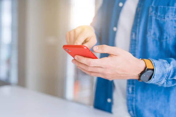 Primer plano de las manos del hombre usando el teléfono inteligente y sonriendo — Foto de Stock