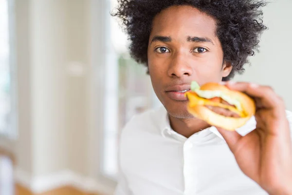 スマートの顔は深刻な思考に自信を持って表現と一緒にお昼を食べるアフリカ系アメリカ人の飢えた男ハンバーガー — ストック写真