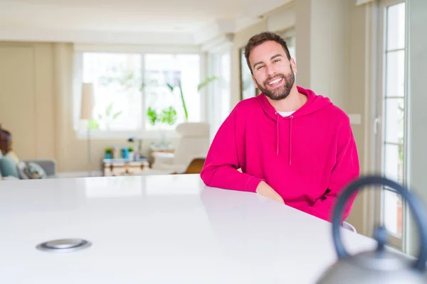 Hombre guapo vistiendo sudadera casual en casa y sonriendo — Foto de Stock