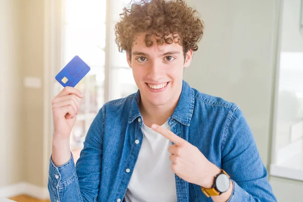 Joven Sosteniendo Tarjeta Crédito Muy Feliz Señalando Con Mano Dedo —  Fotos de Stock