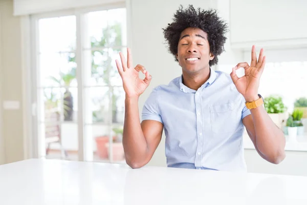 African American business man relax and smiling with eyes closed doing meditation gesture with fingers. Yoga concept.