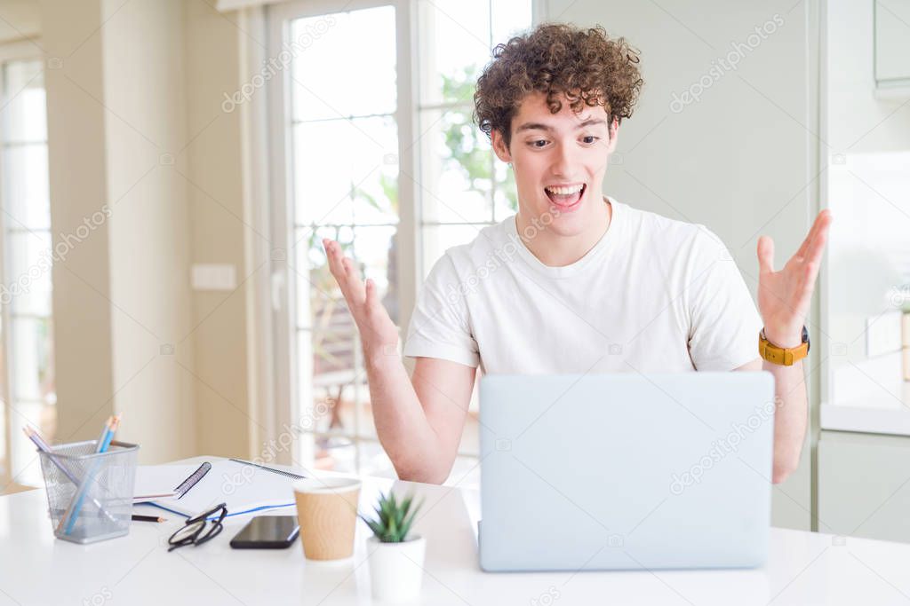 Young student man working and studying using computer laptop very happy and excited, winner expression celebrating victory screaming with big smile and raised hands