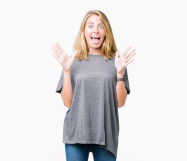 Güzel genç kadın üzerinde büyük boy rahat t-shirt giyen deli kutluyor arka plan izole ve başarı için kaldırdı kollarını açarak hayrete ve heyecanlı çığlık gözleri açık. Kazanan kavramı