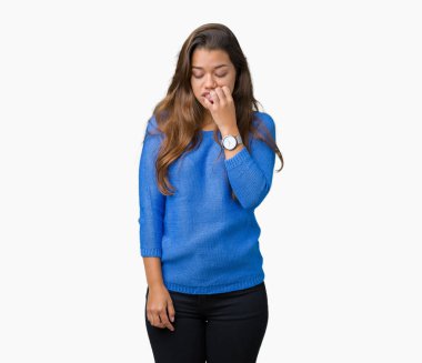 Stresli ve gergin ile izole arka plan üzerinde mavi kazak giyen genç güzel esmer kadın tırnak ısırma dudaklarından eller. Anksiyete sorunu.