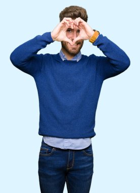 Genç yakışıklı iş yapıyor kalp şekli ile el ve parmak işareti seyir gülümseyen adam