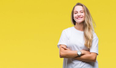 Üzerinde rahat beyaz t-shirt giyen genç güzel sarışın kadın mutlu yüz ile gülümseyerek kameraya seyir silah geçti arka plan izole. Olumlu bir kişi.