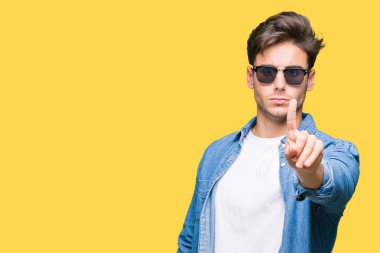 Genç yakışıklı adam giyen güneş gözlüğü izole üzerinde arka plan işaret parmağını ve kızgın ifade ile