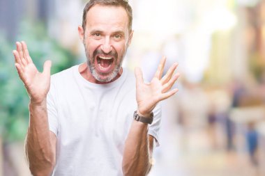 Orta yaş ağarmış komuta sizde üzerinde beyaz t-shirt giyen deli kutluyor arka plan izole ve silah ile başarı için yükseltilmiş ve açık gözleri heyecanlı çığlık hayrete düşürdü. Kazanan kavramı