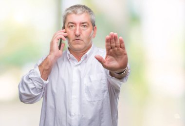 Smartphone ile izole arka plan üzerinde konuşmak kıdemli yakışıklı dur işareti ile ciddi ve kendine güvenen ifade, savunma hareketi yaparken el açmak