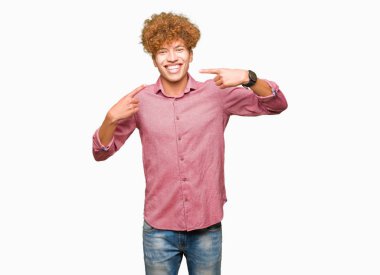 Kendinden emin gösterilen ve işaret parmakları diş ve ağız ile gülümseyen afro saçlı genç yakışıklı işadamı. Sağlık kavramı.