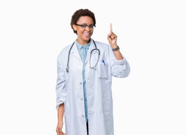 Başarılı fikirle izole arka plan işaret parmağı üzerinde tıbbi ceket giyen genç Afro-Amerikan doktor kadın. Çıktıktan ve mutlu. Bir numara.