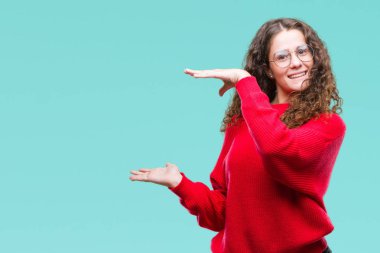 Güzel esmer kıvırcık saçlı Genç kız eller eller büyük gösterilen ve büyük boy işareti, ölçü birimi sembolü ile izole arka plan üzerinde gözlük ve kış kazak giyiyor. Kameraya bakarak gülümsüyordu. Ölçüm kavramı.