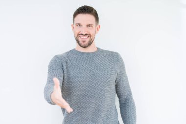 Yakışıklı genç dostu sunan karşılıklı tebrik ve davet edici gülümseyen izole arka plan üzerinde rahat kazak giyiyor. Başarılı iş.