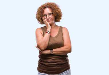 Orta yaş İspanyol kadın seyir yorgun ve bıkkın ile depresyon sorun Çapraz kollar ile izole arka plan düşünme üzerinde gözlük.