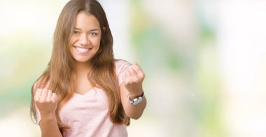 Gülümseyen ve başarı için çığlık izole arka plan çok mutlu ve heyecanlı kaldırdı, silah ile kazanan jest yapıyor üzerinde pembe t-shirt giyen genç güzel esmer kadın. Kutlama kavramı.