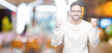 Yakışıklı delikanlı izole arka plan üzerinde kutluyor gözlük takan şaşırttı ve başarı için kaldırdı kollarını açarak hayret ve gözleri açık. Kazanan kavramı.