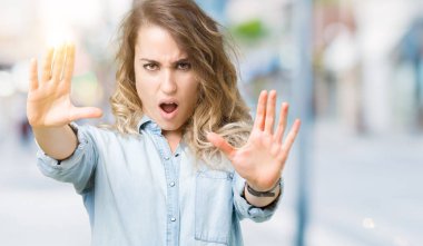 Şokta bağırarak güzel genç sarışın kadın yüzünden arka plan bulanık korkuyor ve korku ifade dur hareketi el ile ile dehşete. Panik kavramı.