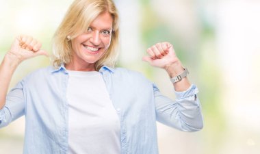 Yüzünde gülümseme ile kendinden emin görünüyorsun, kendini gururlu ve mutlu parmakları ile işaret izole arka plan orta yaş sarışın kadın.