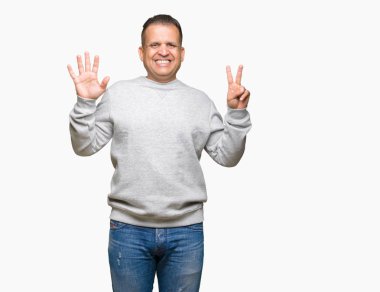 Gösterilen arka plan üzerinde spor kazak giyen orta yaş Arap adam izole ve parmakları ile işaret kendinden emin ve mutlu gülümseyerek süre yedi numara.