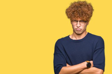 Afro yüz çapraz kolları üzerinde gözlük şüpheci ve sinir, onaylamayan ifade giyen genç yakışıklı adam. Negatif kişi.