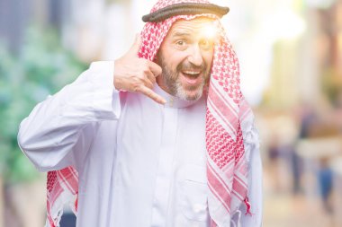 Üst düzey Arap adamın yaptığını gülümseyen izole arka plan üzerinde keffiyeh giydiğini telefon hareketi ile el ve parmak telefonda konuşuyor gibi. Kavramları iletişim.