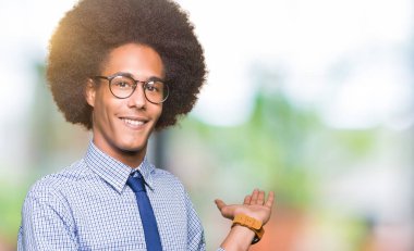 Genç Afro-Amerikalı iş adamı afro saçlı gözlüklü açık el ile doğal gülümseyen girmek için davet