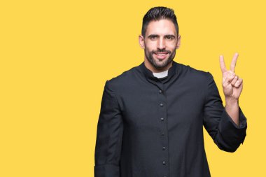 Genç Hıristiyan rahip gösterilen ve parmakları ile işaret izole arka plan üzerinde ikincisi ise kendinden emin ve mutlu gülümseyerek.