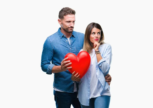 Young Couple Love Holding Red Heart Isolated Background Serious Face — Stock Photo, Image